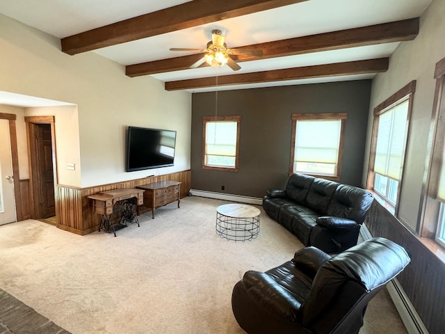 living area with baseboard heating, wainscoting, and a healthy amount of sunlight