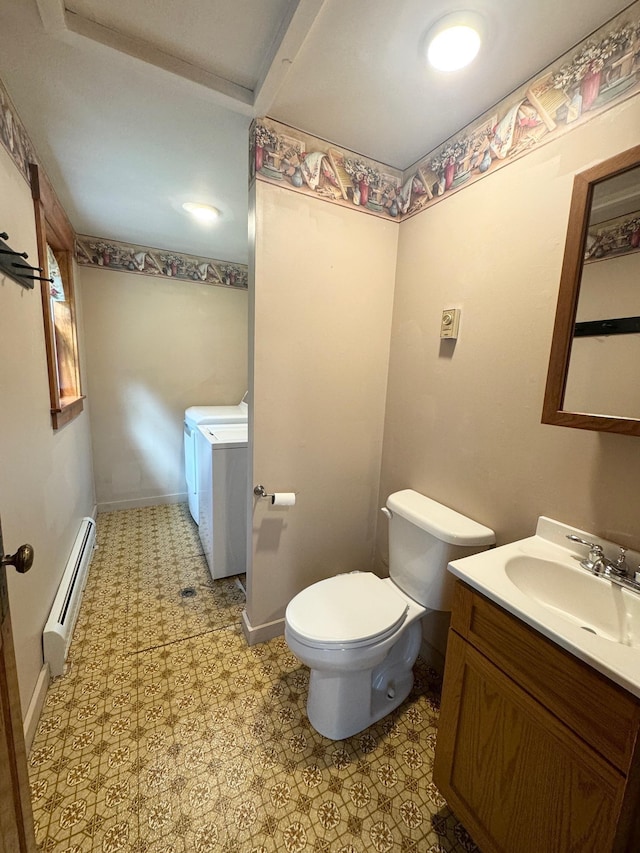 half bathroom featuring washing machine and clothes dryer, a baseboard radiator, toilet, vanity, and baseboards