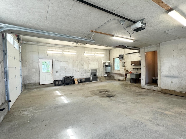 garage featuring water heater, a sink, and a garage door opener