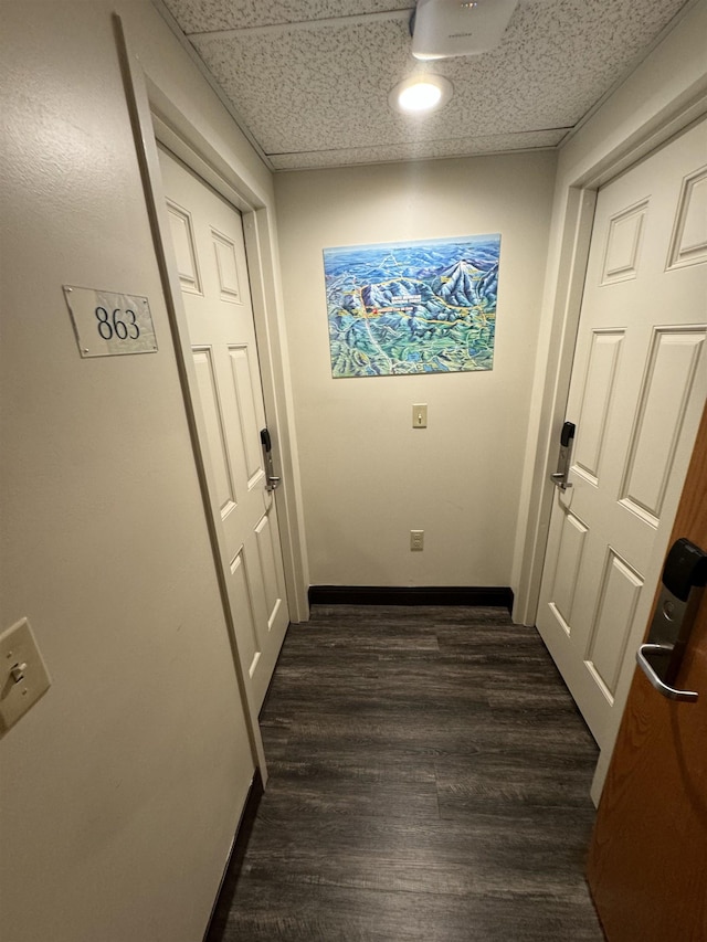 corridor featuring dark wood-style flooring and baseboards