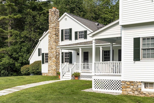 view of front of property with a front lawn, roof with shingles, a porch, and a chimney