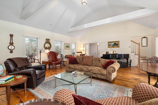 living room with hardwood / wood-style flooring, high vaulted ceiling, and stairs