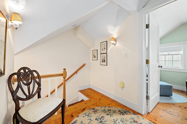 living area with lofted ceiling, hardwood / wood-style flooring, baseboards, and an upstairs landing