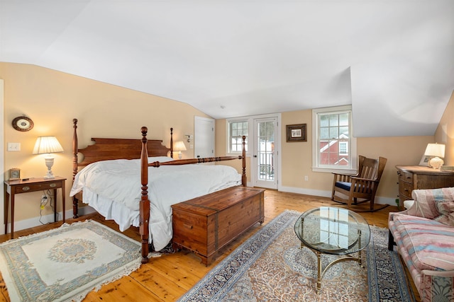 bedroom with lofted ceiling, access to exterior, baseboards, and wood finished floors