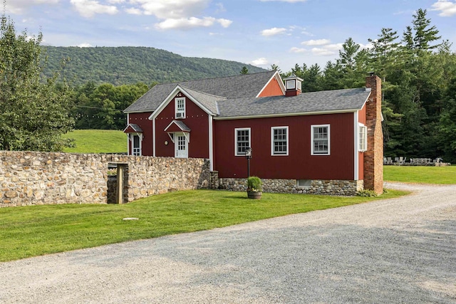 view of home's exterior featuring a lawn, a shingled roof, and a chimney