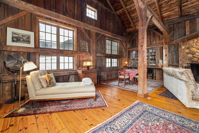 living area featuring wooden ceiling, wooden walls, and high vaulted ceiling