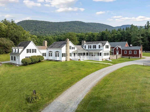 exterior space featuring a chimney, a front lawn, driveway, covered porch, and a mountain view
