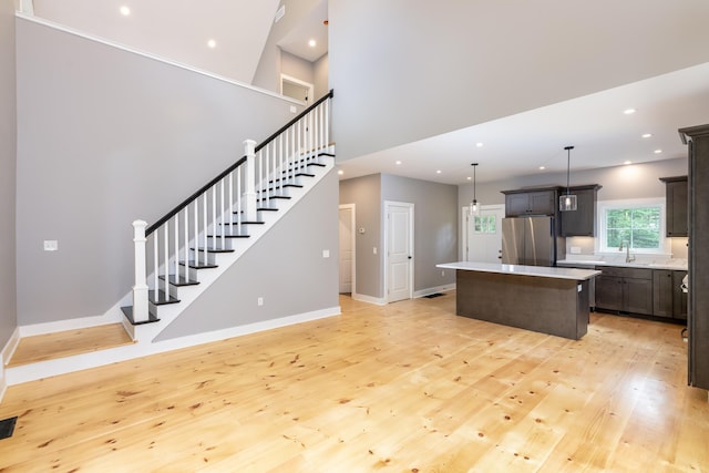 kitchen featuring a center island, recessed lighting, freestanding refrigerator, a sink, and light wood-type flooring