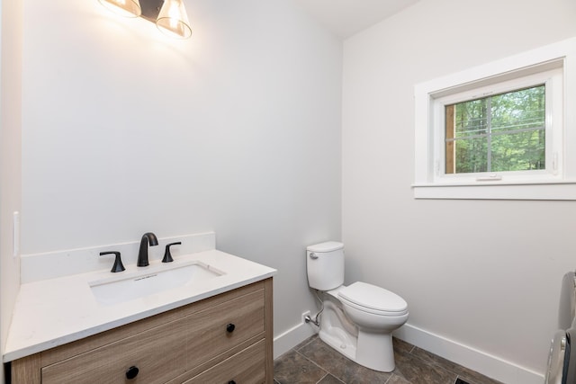 bathroom featuring toilet, baseboards, and vanity