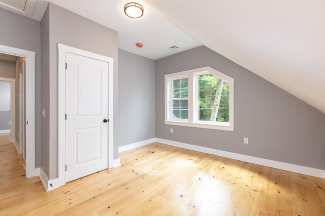 bonus room featuring lofted ceiling, visible vents, light wood-style flooring, and baseboards