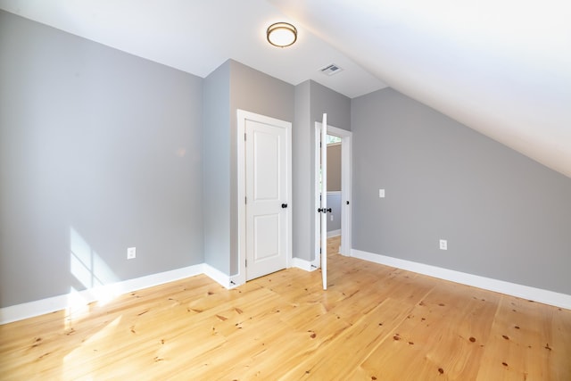 additional living space featuring lofted ceiling, baseboards, visible vents, and light wood finished floors