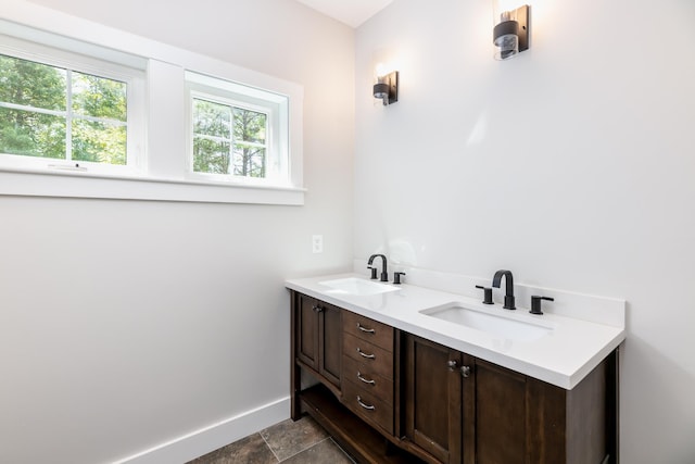 bathroom with double vanity, baseboards, and a sink