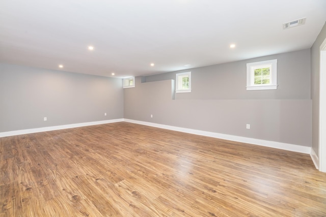 below grade area featuring light wood finished floors, visible vents, and a healthy amount of sunlight