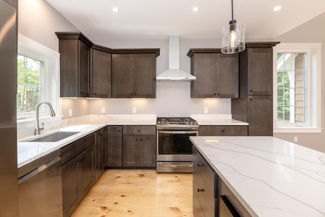 kitchen with a sink, appliances with stainless steel finishes, plenty of natural light, and wall chimney range hood