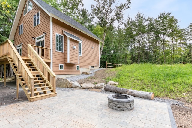 exterior space featuring roof with shingles, a patio, a deck, and stairs