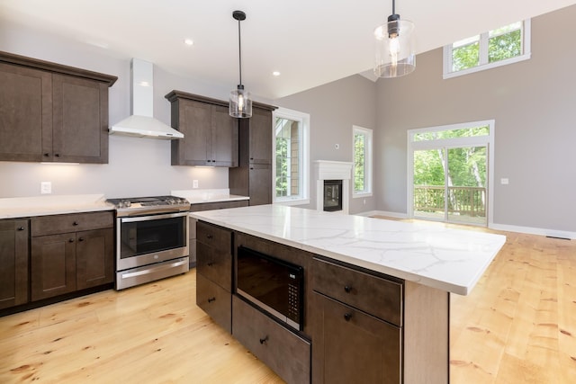 kitchen with black microwave, dark brown cabinetry, light wood-style floors, wall chimney exhaust hood, and gas range