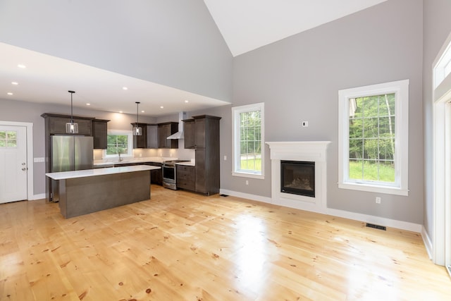 kitchen with dark brown cabinetry, a kitchen island, visible vents, light countertops, and appliances with stainless steel finishes