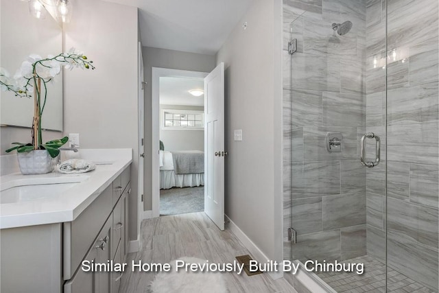 ensuite bathroom featuring a shower stall, ensuite bath, baseboards, and vanity