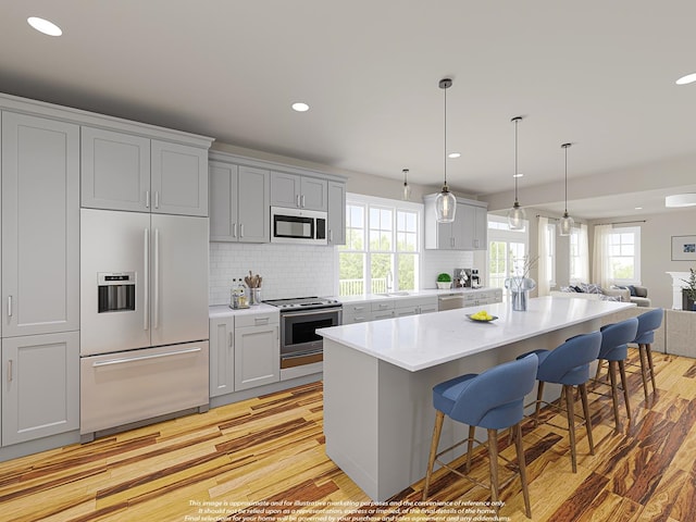 kitchen with a center island, stainless steel appliances, light countertops, a sink, and a kitchen bar