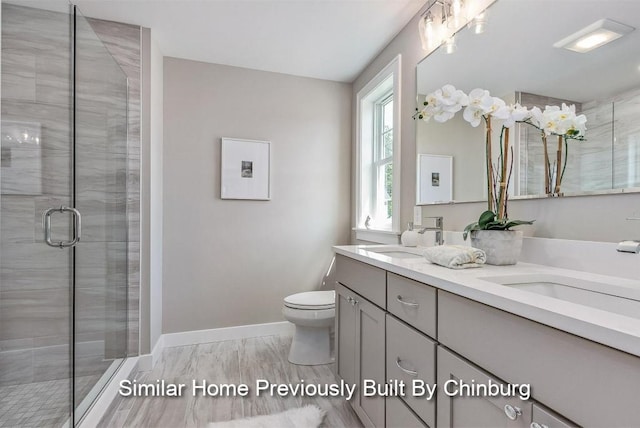 bathroom featuring wood-type flooring, vanity, toilet, and a shower with shower door