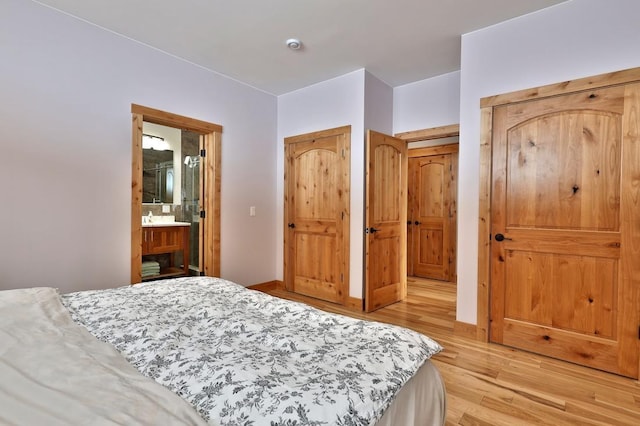 bedroom with light wood finished floors and ensuite bathroom