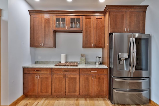 kitchen featuring light wood-style floors, brown cabinetry, and stainless steel fridge