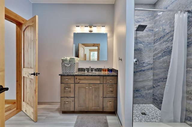 bathroom with a tile shower, vanity, and baseboards