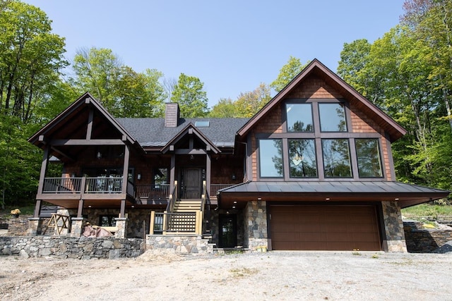 view of front of home featuring a standing seam roof, stone siding, a chimney, and an attached garage