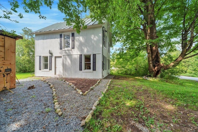 rear view of property featuring metal roof, a standing seam roof, and a lawn