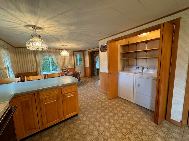 kitchen featuring range, a chandelier, washer and clothes dryer, and hanging light fixtures