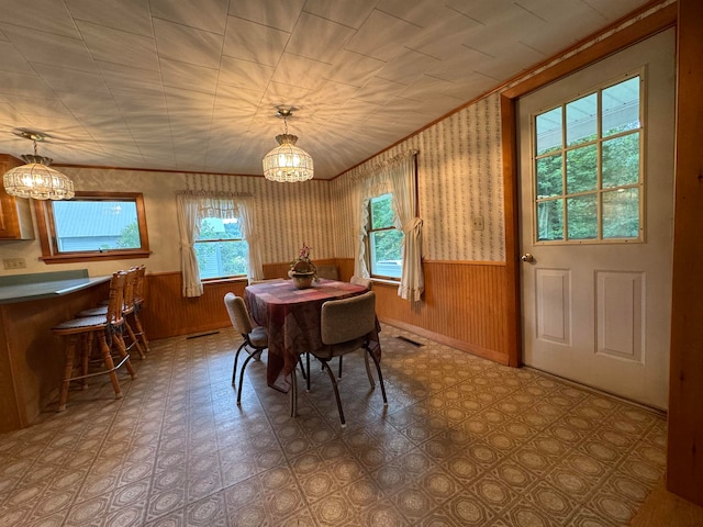 dining area featuring wooden walls and an inviting chandelier