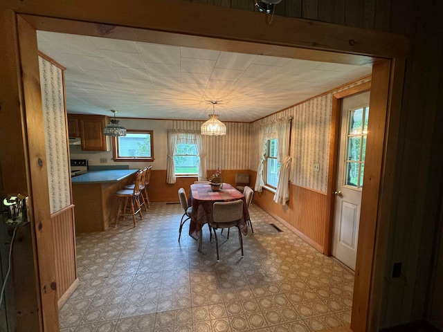 dining area with a chandelier and wood walls