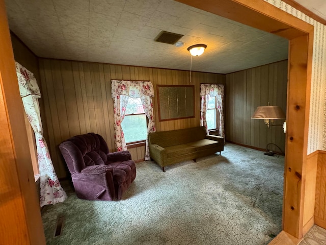 living area with carpet and wood walls