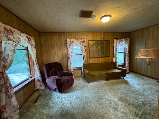 living area with light carpet and wooden walls