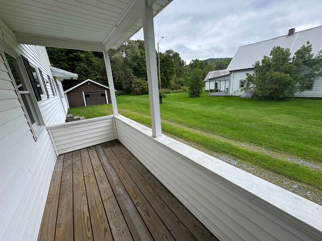 wooden terrace with a garage, a yard, and an outbuilding