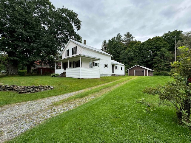 exterior space featuring a garage, covered porch, an outdoor structure, and a lawn