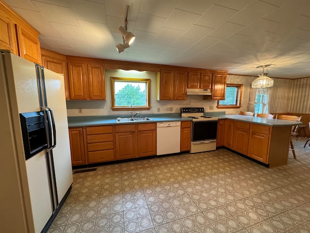 kitchen with white appliances, a chandelier, kitchen peninsula, sink, and hanging light fixtures