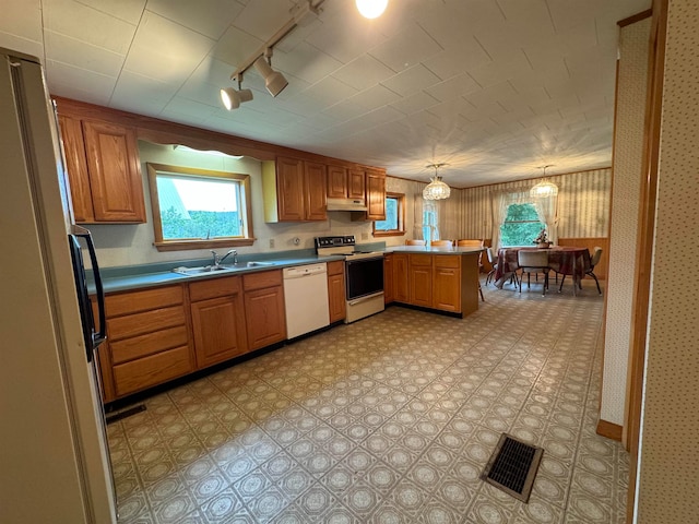 kitchen featuring white appliances, pendant lighting, kitchen peninsula, sink, and rail lighting