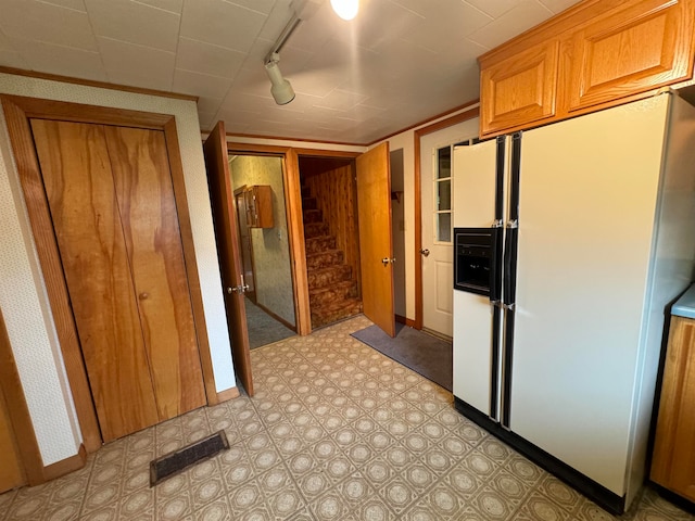 kitchen featuring rail lighting and white fridge with ice dispenser