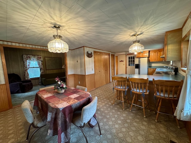 dining area featuring sink, an inviting chandelier, and wooden walls