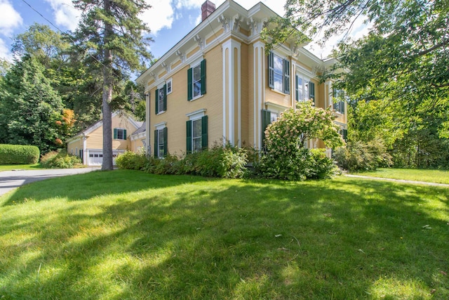 exterior space with a garage, a chimney, and a lawn