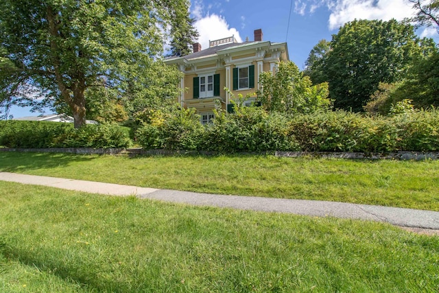 italianate house featuring a front lawn, a chimney, and stucco siding