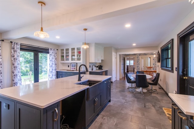 kitchen featuring recessed lighting, a sink, white cabinets, hanging light fixtures, and an island with sink