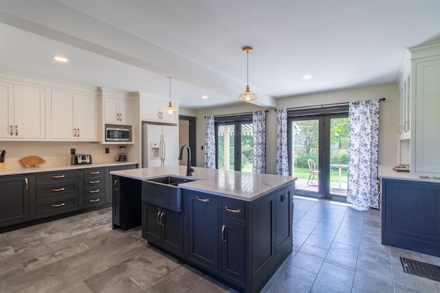 kitchen featuring a sink, white cabinets, light countertops, white fridge with ice dispenser, and stainless steel microwave