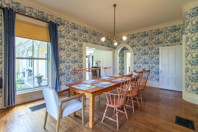 dining area featuring arched walkways, wood finished floors, visible vents, and wallpapered walls