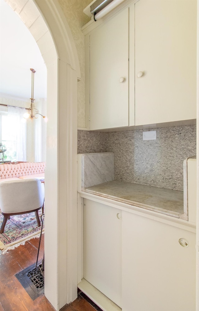 interior space featuring arched walkways, wood finished floors, and backsplash