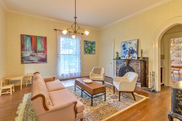 living area with a notable chandelier, crown molding, arched walkways, and wood finished floors