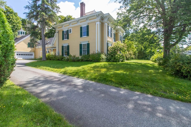 view of front of property with a garage, a chimney, and a front yard