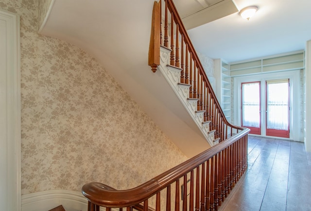 stairs with wood-type flooring and wallpapered walls