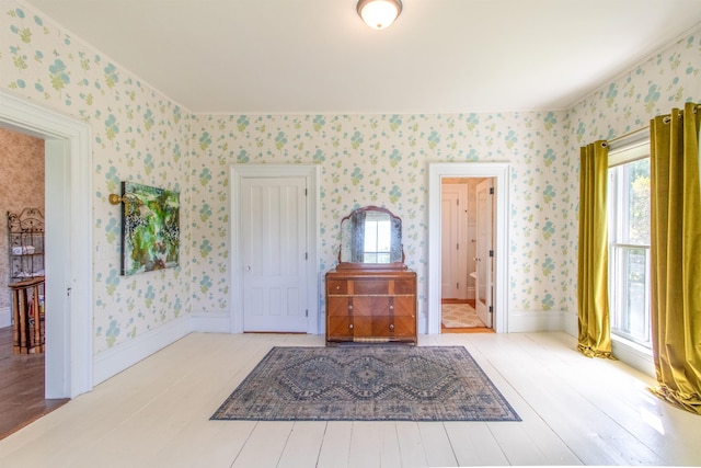 foyer entrance with baseboards, wood finished floors, and wallpapered walls